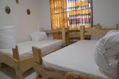 a small room with two beds and a window at Kienyeji Wooden Rest Arusha in Nkoanrua