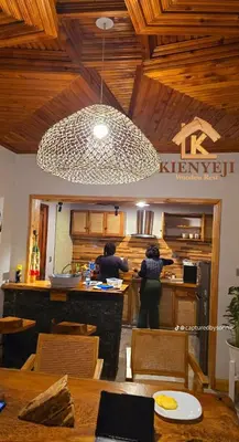 two women standing in a kitchen with a counter at Kienyeji Wooden Rest Arusha in Nkoanrua