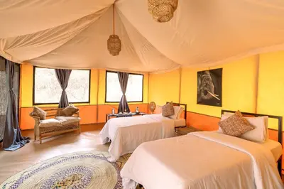 two beds in a room with yellow walls and windows at Ndutu Bush Camp in Endulen