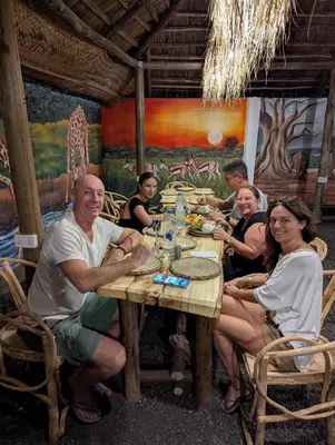 a group of people sitting around a wooden table at Woodland villa in Arusha