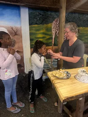 a woman and two girls standing next to a table with a cake at Woodland villa in Arusha
