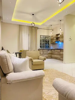 a living room with a couch and chairs and a kitchen at Ellys home Arusha in Arusha