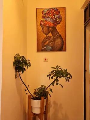 a painting of a woman on a wall with two plants at Rest Stop Home in Arusha