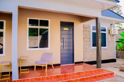 a house with a blue door and chairs outside at Ezma-homes in Boma la Ngombe