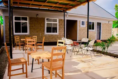 a patio with chairs and tables and a building at Ezma-homes in Boma la Ngombe