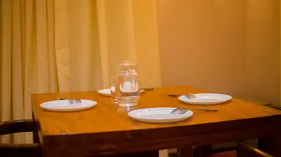a wooden table with plates and a glass of water at The Valley Retreat in Arusha