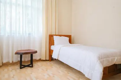 a bedroom with a bed and a stool and a window at The Valley Retreat in Arusha