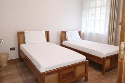 two twin beds in a room with a window at The Valley Retreat in Arusha