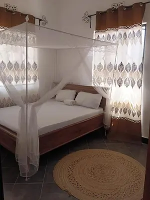 a bedroom with a canopy bed with curtains and a rug at Zebra Homestay in Mto wa Mbu