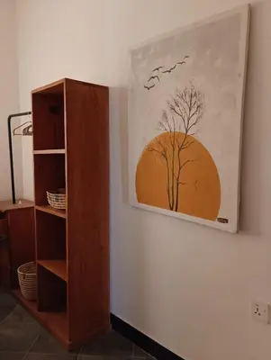a painting of a tree on a wall next to a shelf at Zebra Homestay in Mto wa Mbu