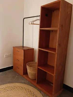 a wooden book shelf next to a dresser at Zebra Homestay in Mto wa Mbu