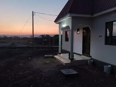 a small white house with the sunset in the background at Zebra Homestay in Mto wa Mbu
