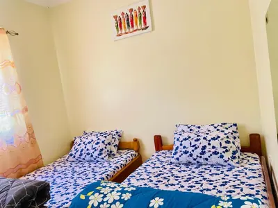 two beds in a room with blue and white sheets at KidotuiVillaHome in Arusha