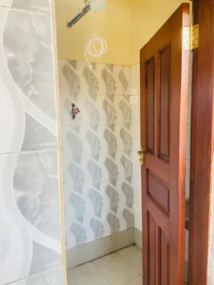 a bathroom with a door and a wall at KidotuiVillaHome in Arusha