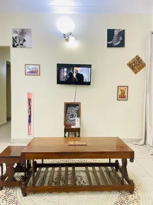 a living room with a wooden table and pictures on the wall at KidotuiVillaHome in Arusha
