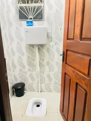 a bathroom with a toilet and a window and a door at KidotuiVillaHome in Arusha