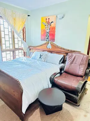 a bedroom with a bed and a couch and a chair at KL shadow homes in Arusha
