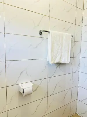 a white tiled bathroom with a roll of toilet paper at KL shadow homes in Arusha