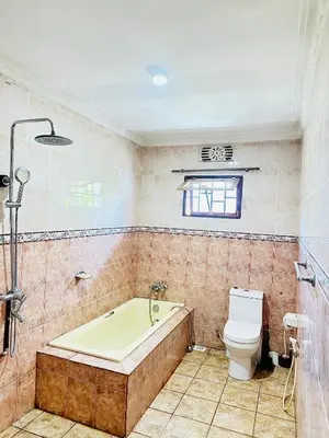 a bathroom with a bath tub and a toilet at KL shadow homes in Arusha