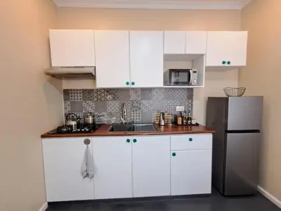 a kitchen with white cabinets and a stainless steel refrigerator at Mboyahomes in Arusha