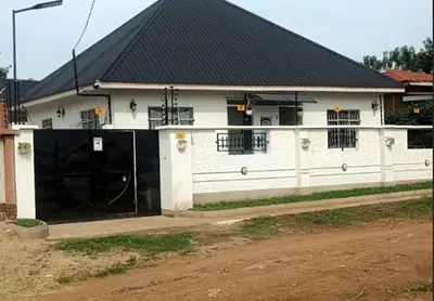 a white house with a black roof and a gate at Five Zones - Private 4-Bedroom Holiday Home in Moshi