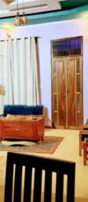 a living room with a blue couch and a door at Kilimanjaro Forest Lodge and Camping Site in Mdawi