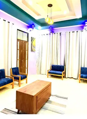 a living room with blue chairs and a coffee table at Kilimanjaro Forest Lodge and Camping Site in Mdawi