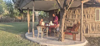 a group of people sitting at a table under a tree at Lake Natron Maasai Boma-Unique Stay in Mtowabaga