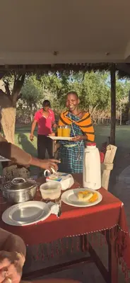 a man sitting at a table with plates of food at Lake Natron Maasai Boma-Unique Stay in Mtowabaga