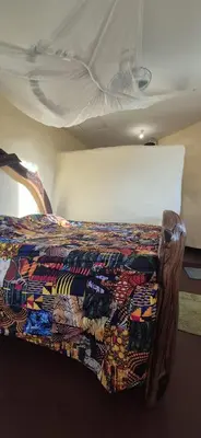 a bed with a colorful blanket on top of it at Lake Natron Maasai Boma-Unique Stay in Mtowabaga