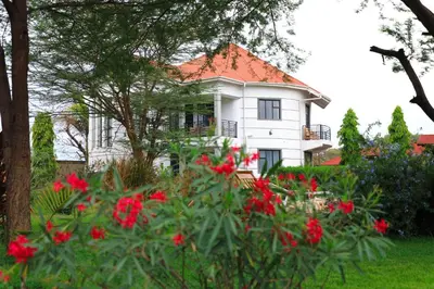 a white house with red flowers in front of it at Heart Of Africa Lodge Acacia in Mkulat