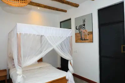 a bedroom with a bed with a canopy and a picture of a zebra at Heart Of Africa Lodge Acacia in Mkulat
