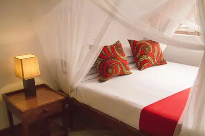 a bedroom with a bed with red and white pillows at Heart Of Africa Lodge Acacia in Mkulat
