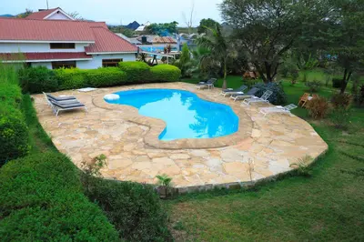 a swimming pool in a yard with chairs around it at Heart Of Africa Lodge Acacia in Mkulat
