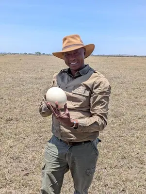 a man in a hat holding a ball in a field at Morris Eco Safaris in Arusha