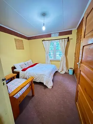 a bedroom with two beds and a window at NgareSero Haven - Eco 3BR Home with Garden and Farm in Usa River