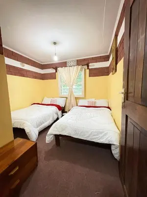 a bedroom with two beds and a window at NgareSero Haven - Eco 3BR Home with Garden and Farm in Usa River