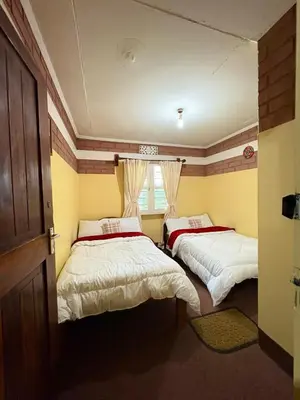 a room with two beds and a window at NgareSero Haven - Eco 3BR Home with Garden and Farm in Usa River