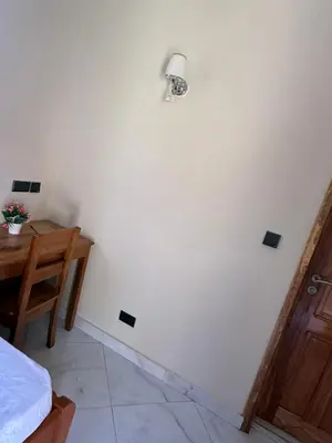 a room with a white wall with a lamp and a table at Safari Haven Villa in Moshi