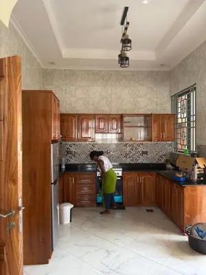 a woman standing in a kitchen preparing food at Safari Haven Villa in Moshi