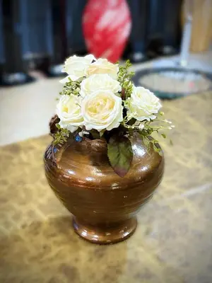 a vase filled with white roses sitting on a table at Esther Villas Home in Boma la Ngombe