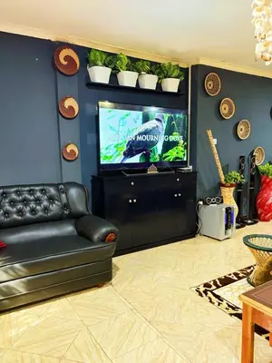 a living room with a black leather couch and a tv at Esther Villas Home in Boma la Ngombe