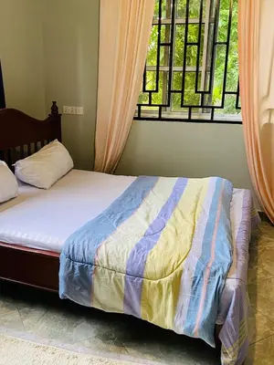 a bed in a room with a window and a bed sidx sidx sidx at Tulivu Nyumba in Arusha