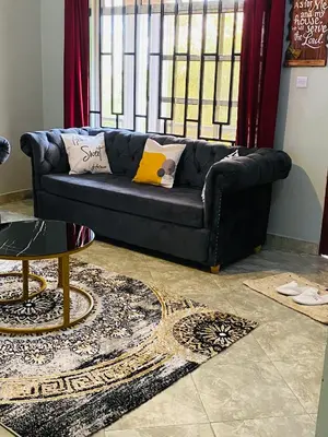 a black couch in a living room with a window at Tulivu Nyumba in Arusha