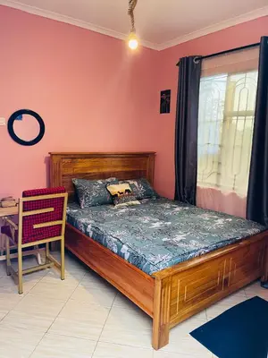 a bedroom with a wooden bed and a window at Moshi -Mnazi home stay in Moshi