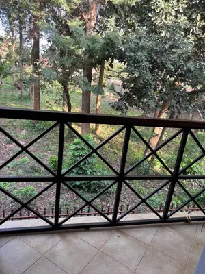a fence with a view of a field with trees at Cozy and stylish apartment in Arusha Town in Arusha