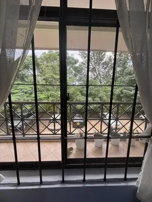 an open window with three plants on a balcony at Cozy and stylish apartment in Arusha Town in Arusha