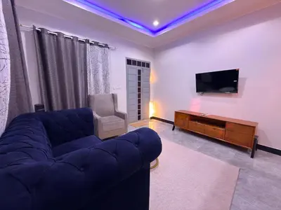 a living room with a blue couch and a tv at Kilimanjaro Peponi Villas in Msaranga