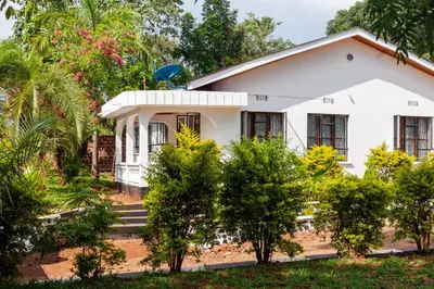 a white house with trees in front of it at Noric Homes and Adventure in Msaranga
