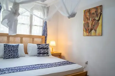 a bedroom with a bed with blue and white pillows at Noric Homes and Adventure in Msaranga
